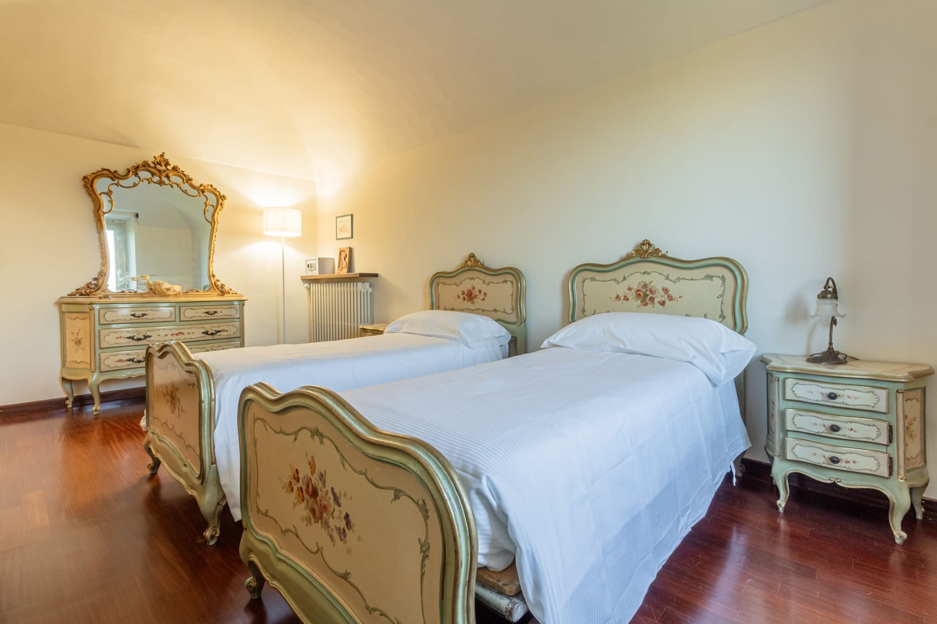 Un dormitorio con dos camas, un aparador, una mesita de noche y un espejo.