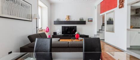 A modern living room with a sofa, TV, and decorative items.