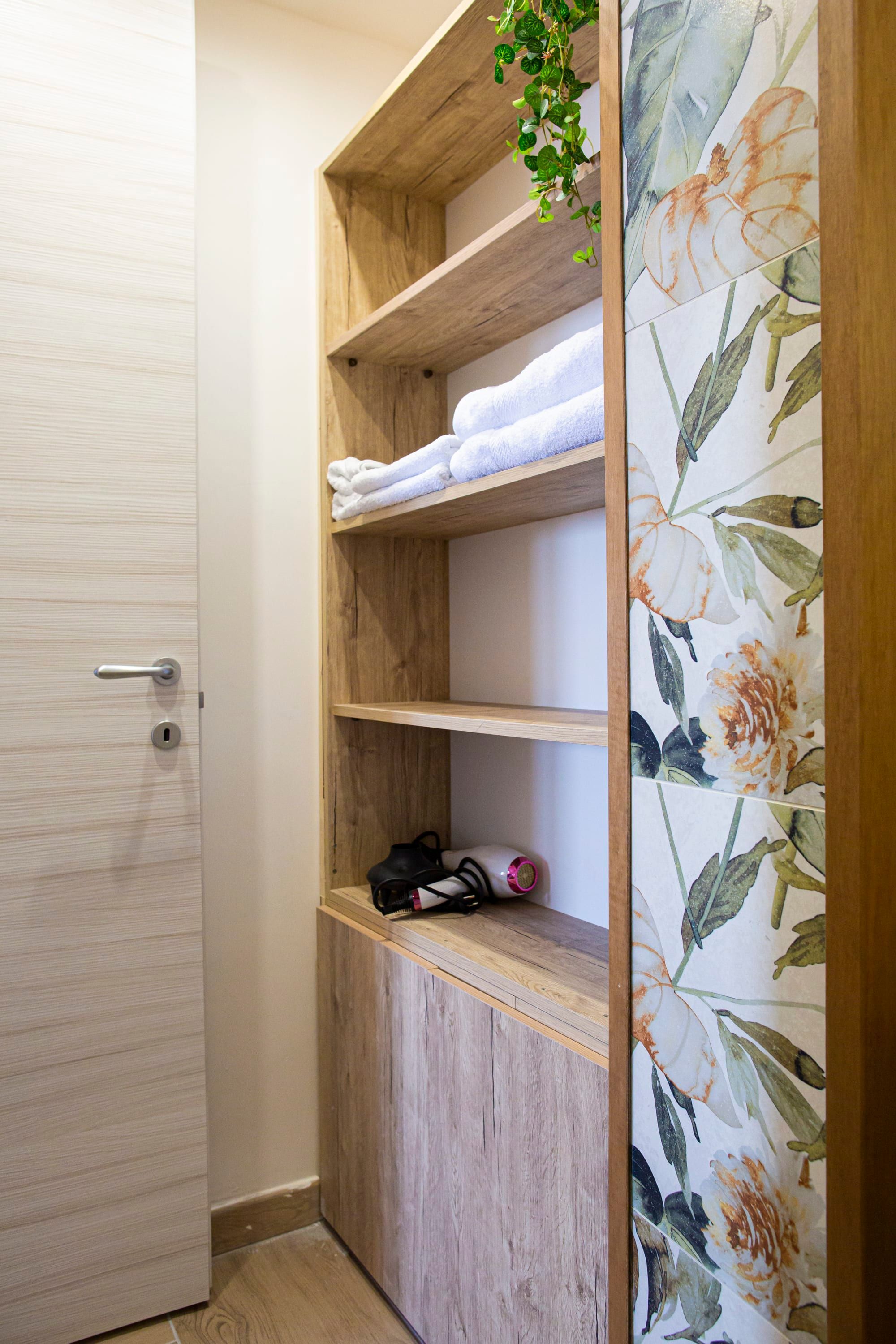 A wooden shelf unit with towels and a hairdryer.