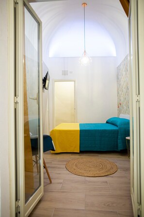 A room with a bed, a round rug, a hanging light fixture, and a door. - Charming Casa Tilia by the old Town (Catania)