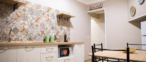 A kitchen with a patterned backsplash, a microwave, and a dining area with a table and chairs.