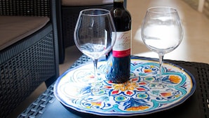 Una mesa con una botella de vino y dos copas sobre una bandeja decorativa.
