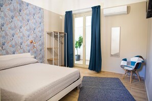 Ein Schlafzimmer mit einem Bett, einem Kleiderschrank, einem Sessel und einer Zimmerpflanze.