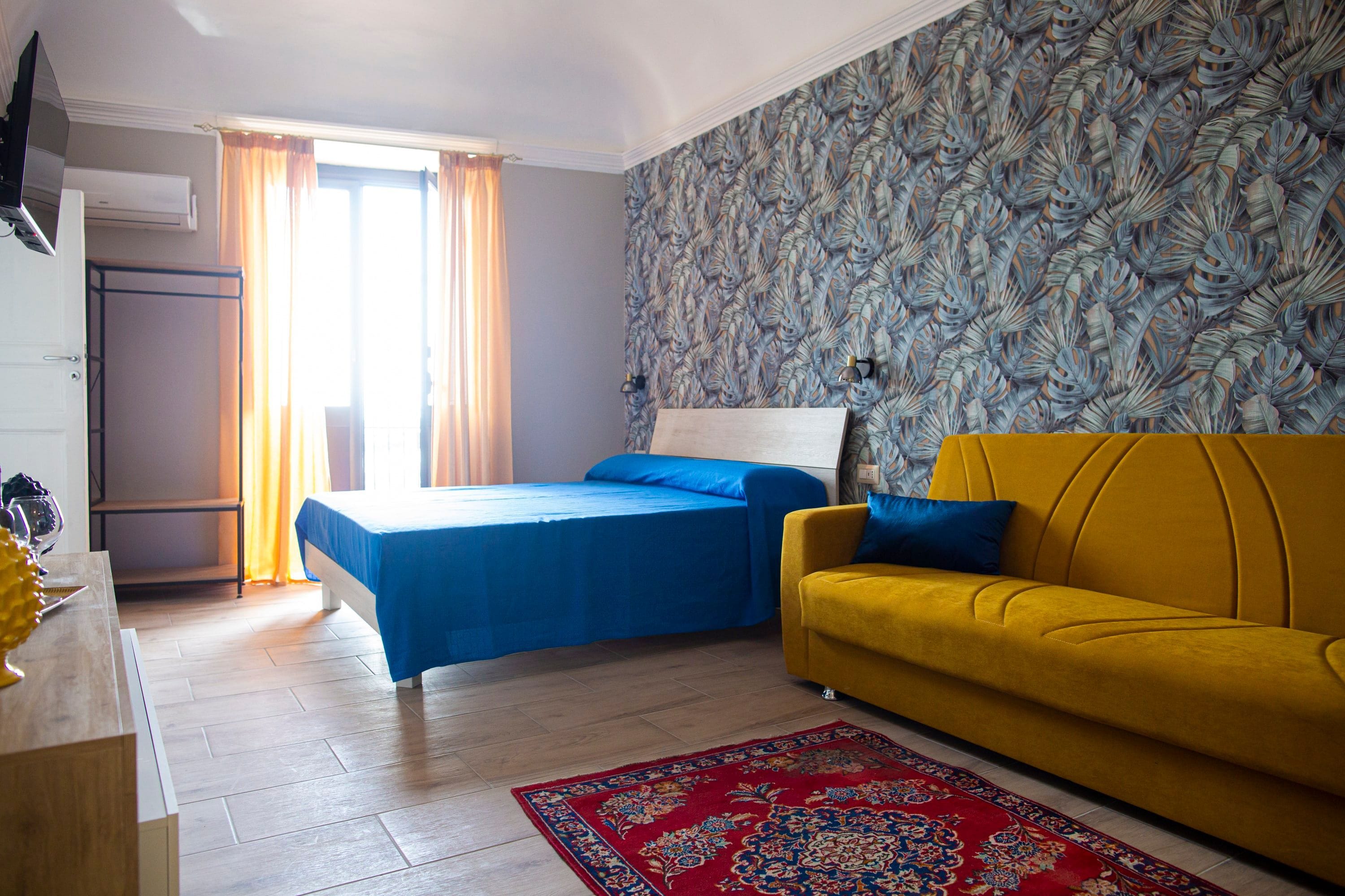 Une chambre à coucher avec un lit, un canapé, un bureau et un mur décoré de motifs.