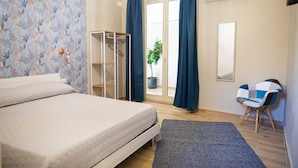 Un dormitorio con cama, armario, silla y ventana con cortinas.