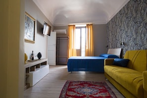 A bedroom with a bed, a sofa, a TV, and a wardrobe. - Charming Casa Tilia by the old Town (Catania)
