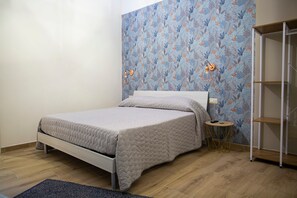 Ein Schlafzimmer mit Bett, Nachttisch, Lampe und Kleiderschrank.