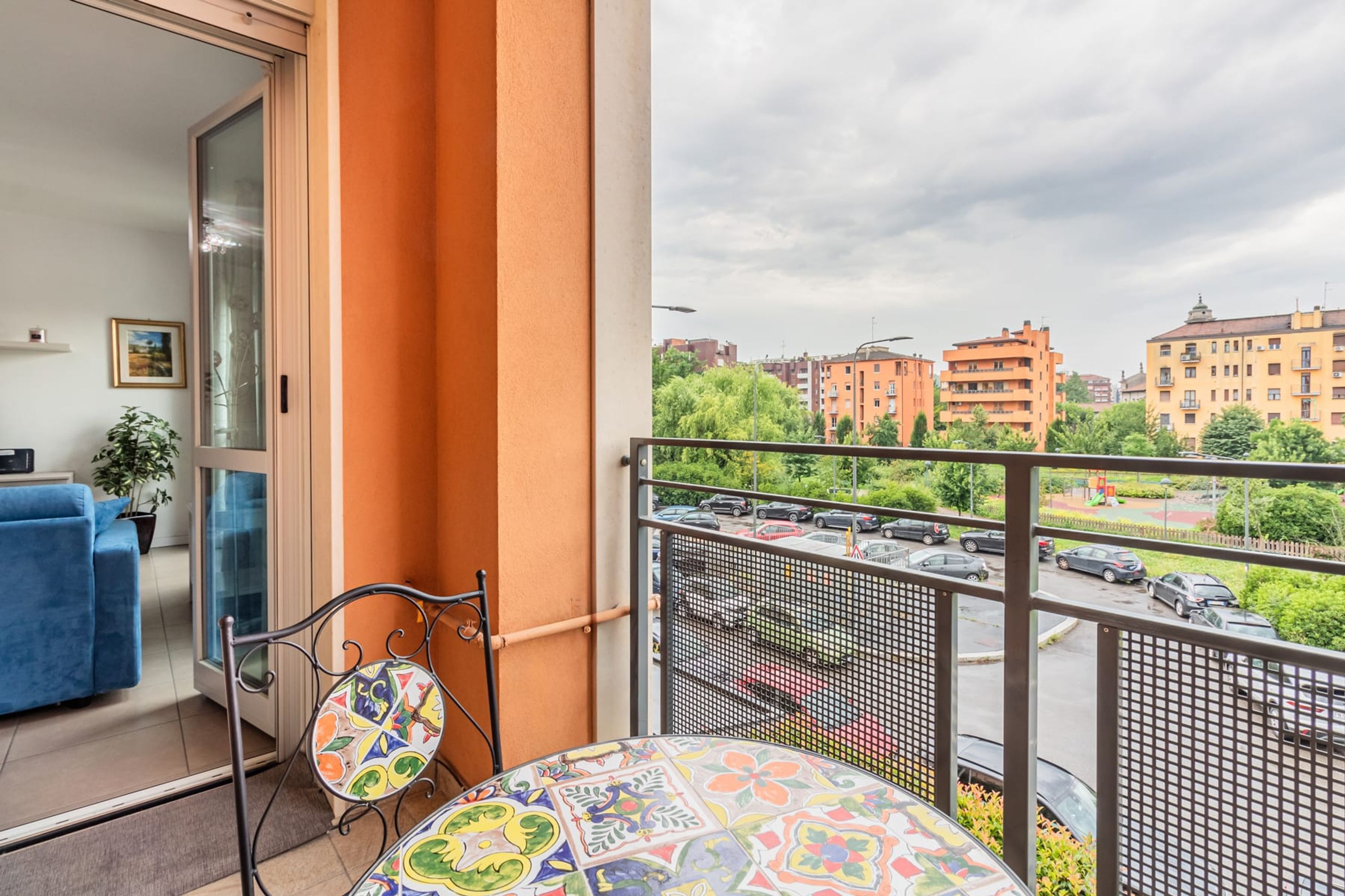 Un balcon avec une table à motifs, un canapé bleu et une plante en pot.