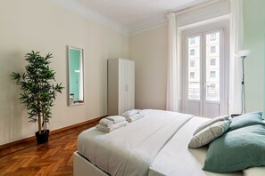 A bedroom with a bed, a wardrobe, a potted plant, and a window with a view of buildings. - Dimora Soperga Freshly Designed and Spacious (Milan)