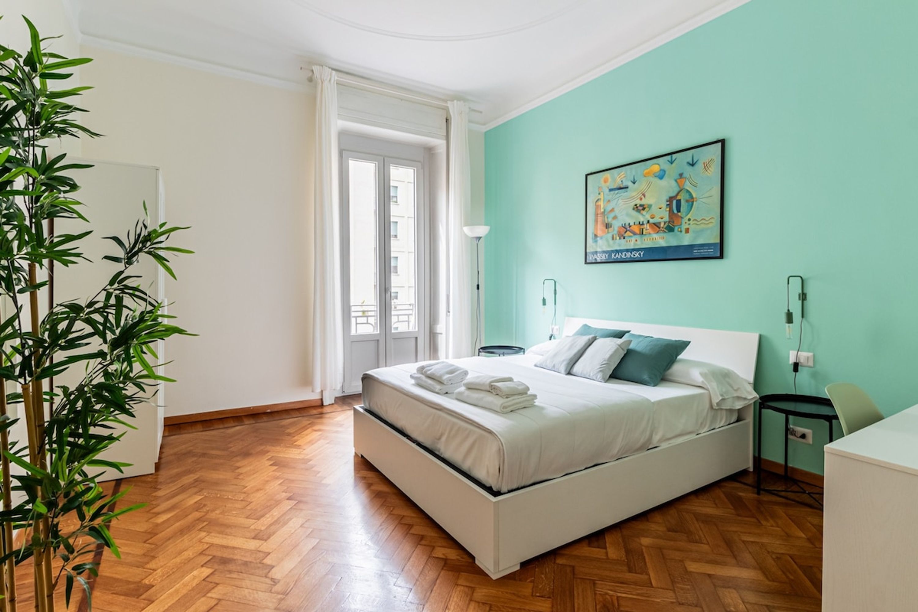Ein Schlafzimmer mit einem Bett, einem Nachttisch, einer Lampe, einem Sessel und einer Pflanze.