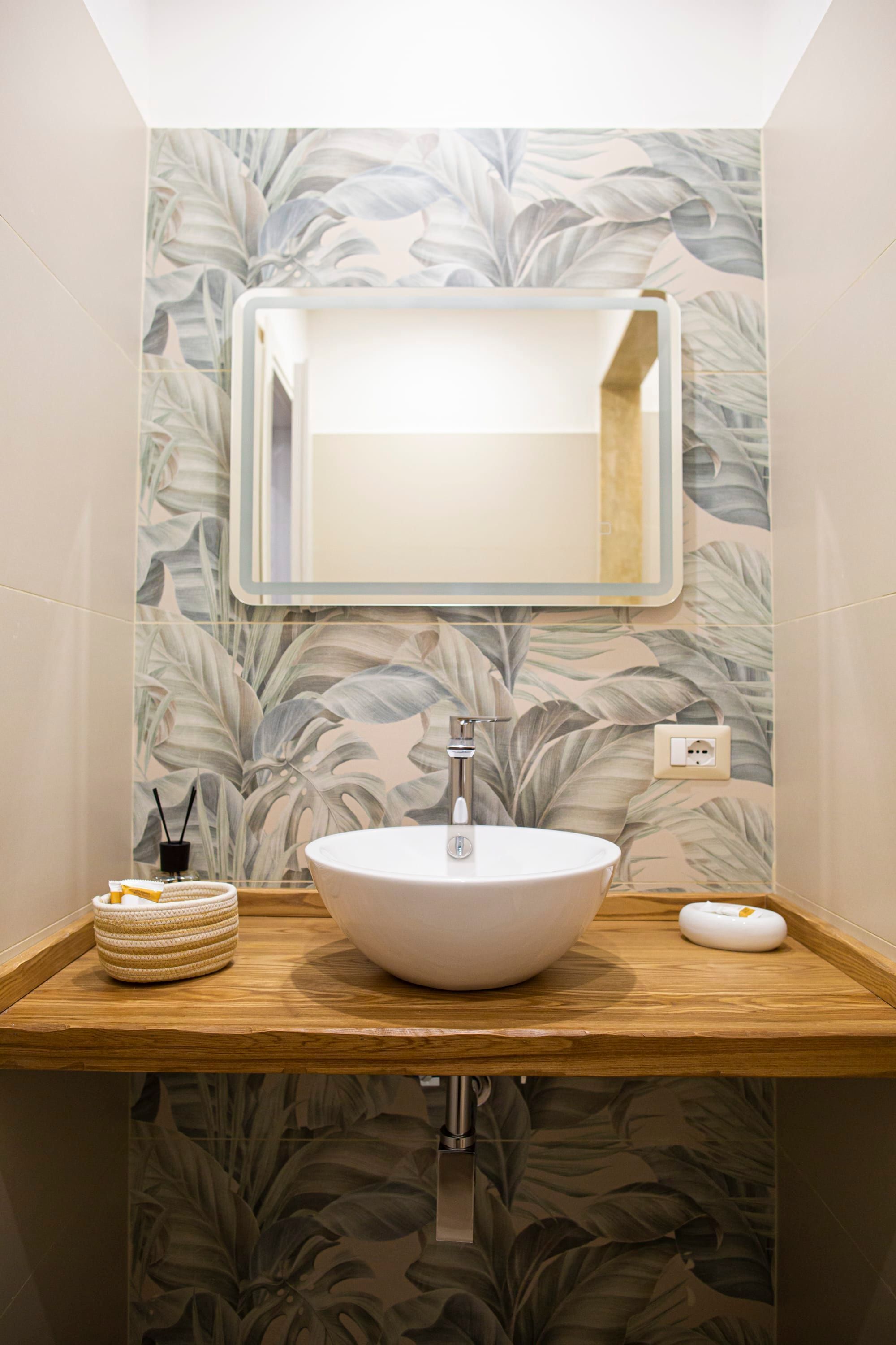 A bathroom with a white sink, a mirror, and a wooden vanity.