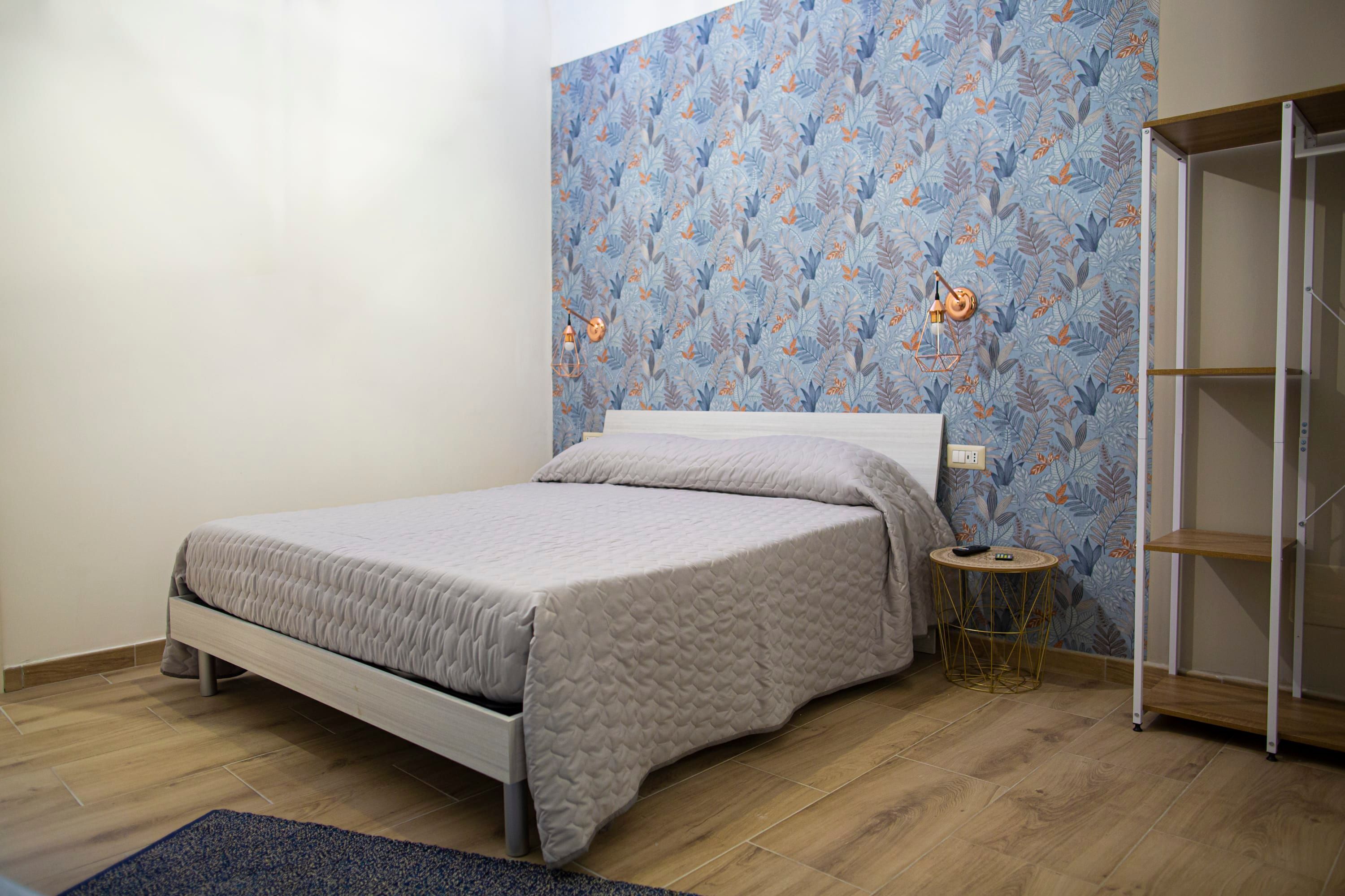 Ein Schlafzimmer mit Bett, Nachttisch, Lampe und Kleiderschrank.