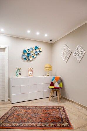Une pièce avec une console blanche, un tapis coloré et des œuvres d’art décoratives accrochées au mur.