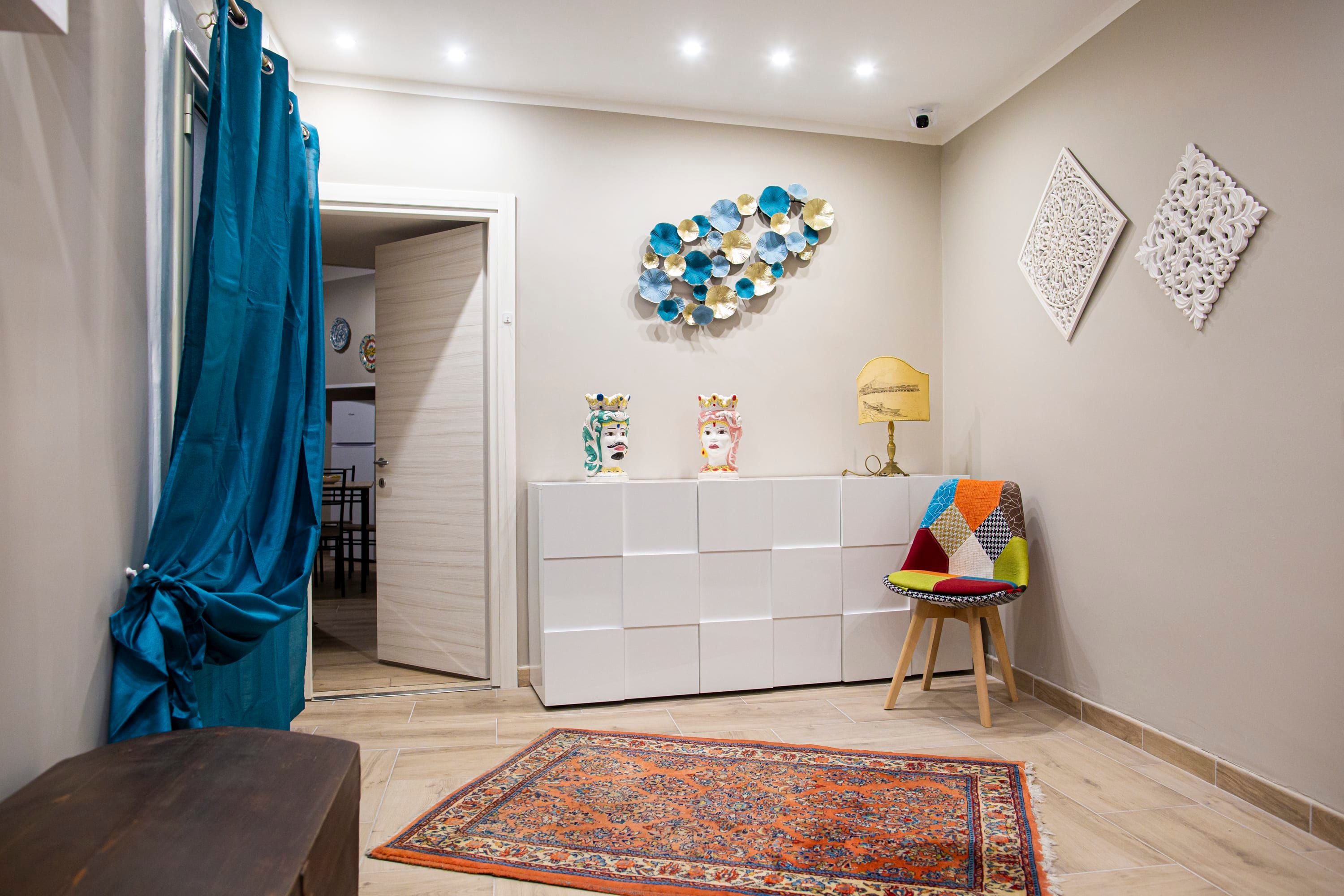 A modern living room with a white cabinet, a colorful rug, and decorative wall art.