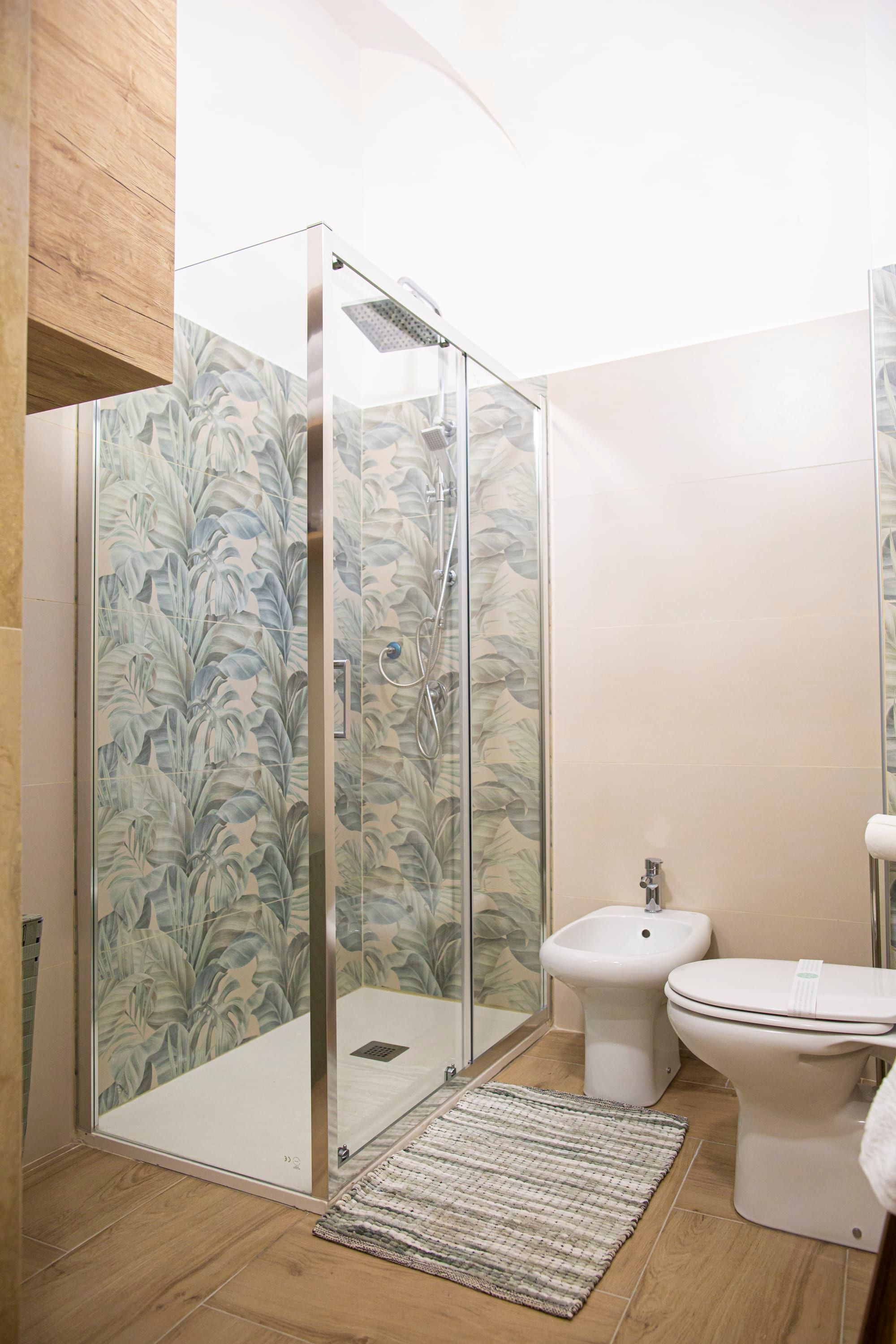 A modern bathroom with a glass-enclosed shower, a bidet, and a toilet.