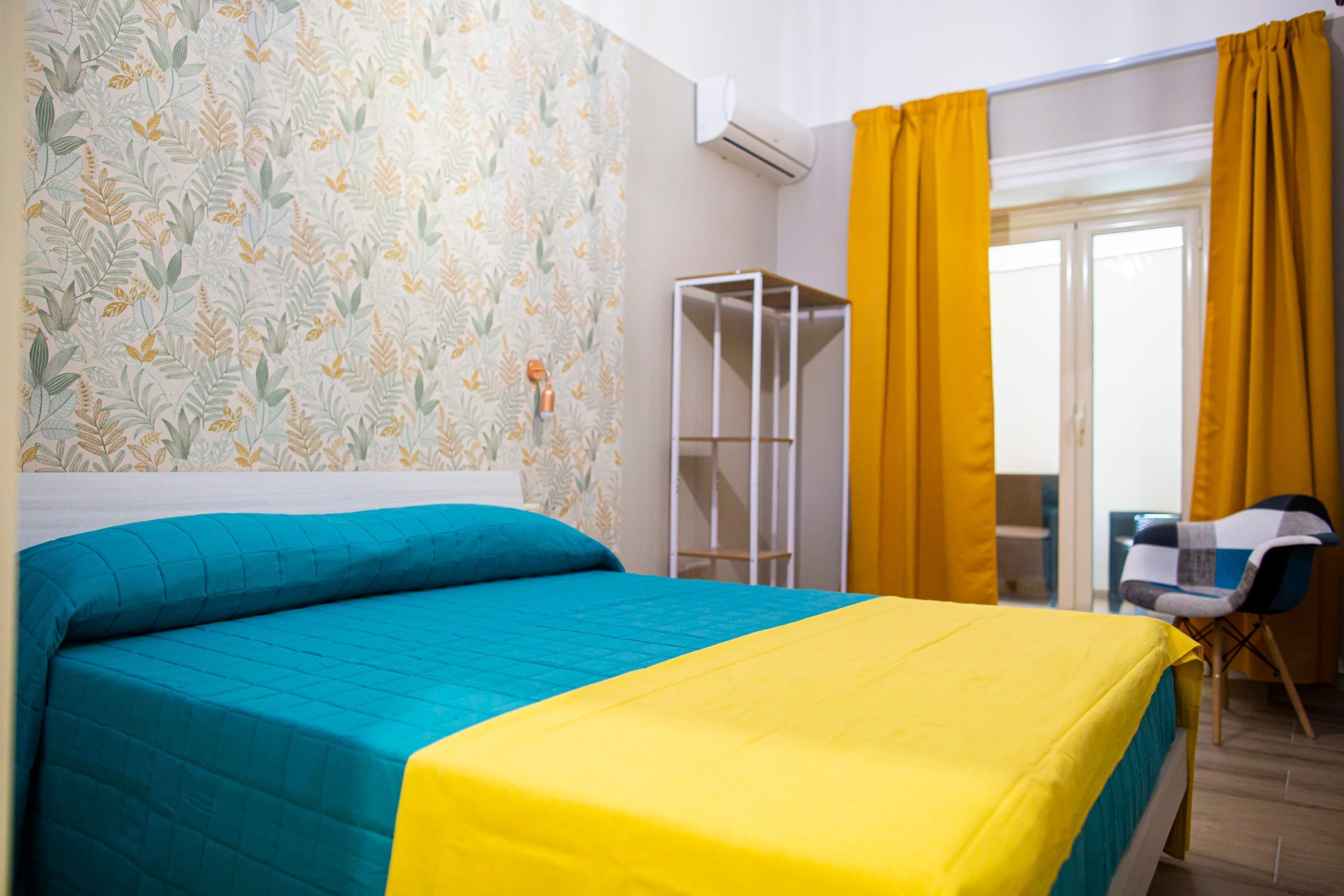 Un dormitorio con cama, armario, silla y ventana con cortinas.