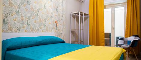 Un dormitorio con cama, armario, silla y ventana con cortinas.