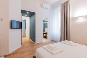 A modern hotel room with a bed, a TV, a bathroom, and a view of the outside. - Casa Isella Stylish and Tranquil (Milan)
