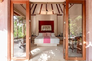 Une chambre à coucher avec un lit, un mur d’accent de couleur rouge et une vue sur l’extérieur.