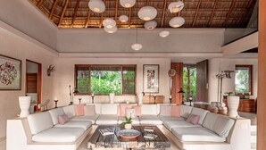 A spacious living room with a high ceiling, large windows, and a central coffee table. - ANANA Casa Cantarena (Tulum)