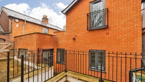 A red brick building with a black metal fence, a window, and a door. - London Street Apt By REDWOOD STAYS (Basingstoke)