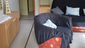 Ein Zimmer mit einem Bett, einem Holzschrank, einem Regal mit Flaschen und einer Uhr an der Wand.