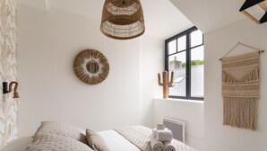 A bedroom with a bed, a window, and a wall-mounted macrame piece. - Ty Peskaiden 2 - Appt vue mer à Cancale (Cancale)