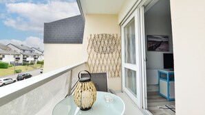 Un balcón con una mesa de vidrio, un farol decorativo y vistas a la calle.