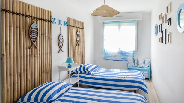 Una habitación con dos camas, un muro de bambú y una ventana con vistas.