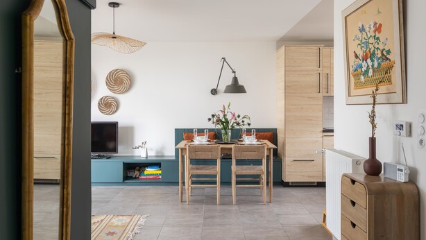A modern living room with a dining table, chairs, a TV, and a large mirror. - Les Sternes - Appt proche de la plage (Saint-Malo)
