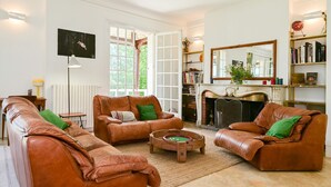 Ein Wohnzimmer mit Ledersofas, einem Kamin, einem Bücherregal und einem Fernseher.