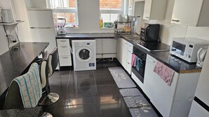 Een kleine keuken met een wasmachine, magnetron en spoelbak.