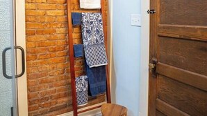 Un pasillo con pared de ladrillo, una puerta de madera y un perchero con toallas.