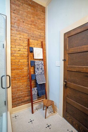 Ein Flur mit Backsteinwand, einer Holztür und einem Handtuchhalter mit Handtüchern.