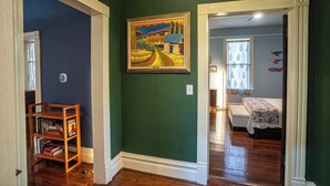 A hallway with a green wall, a wooden bookshelf, and a painting of a landscape. - Little Acres: 2 Bedroom Near Hospitals (Augusta)