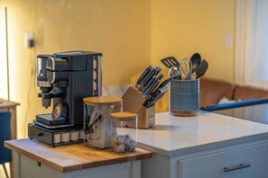 Een keukenblad met een koffiezetapparaat, een messenblok en een houder met keukengerei.