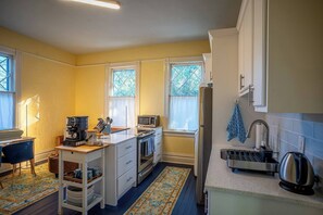 Een compacte keuken met een centraal eiland, een koelkast, een magnetron en een koffiezetapparaat.