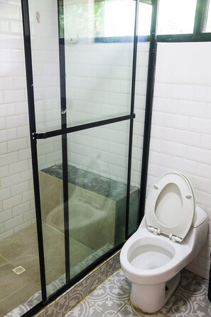 A bathroom with a glass shower enclosure, a toilet, and patterned floor tiles. - Charming 3-bedroom house w/pool, walking distance to the ocean at Bocas del Toro (Bocas del Toro)