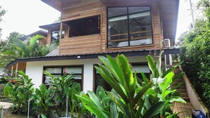 Une maison moderne à deux étages, avec une façade en bois, de grandes fenêtres et un balcon.