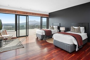 A modern bedroom with two beds, large windows, and a view of the cityscape. - Restio View 11 - Three Bedroom House, Sleeps 6 (Cape Town)