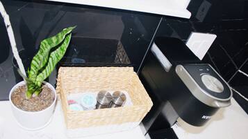 A kitchen counter with a potted plant, a wicker basket containing salt and pepper shakers, and a coffee maker.