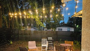 An outdoor patio with a brick floor, wooden chairs, and a table.