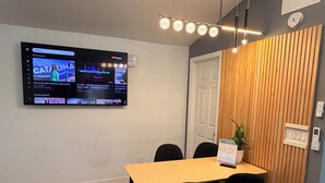 A modern conference room with a flat-screen TV mounted on the wall displaying a YouTube video, a wooden accent wall, a door, and a potted plant.