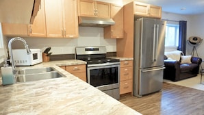 A modern kitchen with stainless steel appliances, wooden cabinets, and a marble countertop.