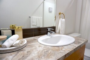 Un bagno con lavandino bianco, uno specchio e un porta asciugamani.