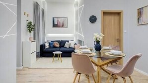 Een moderne woonkamer met een bank, een eettafel met stoelen, en een bijzettafeltje met een vaas.