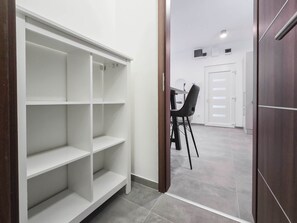 Une pièce avec une étagère blanche, une table à manger et des chaises, et une porte qui donne sur une autre pièce.