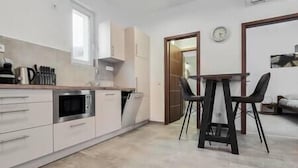 Une cuisine moderne avec des meubles blancs, un four à micro-ondes et un coin repas comprenant une table et des chaises.