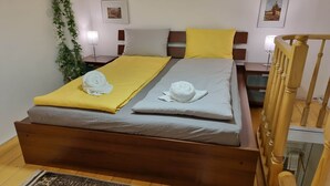A bed with a wooden frame, two pillows, a yellow blanket, and a white towel. - MidTerm - Pody Apartment Budapest (Budapest)