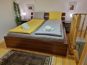 Un lit avec un cadre en bois, deux oreillers, une couverture jaune et une serviette blanche.
